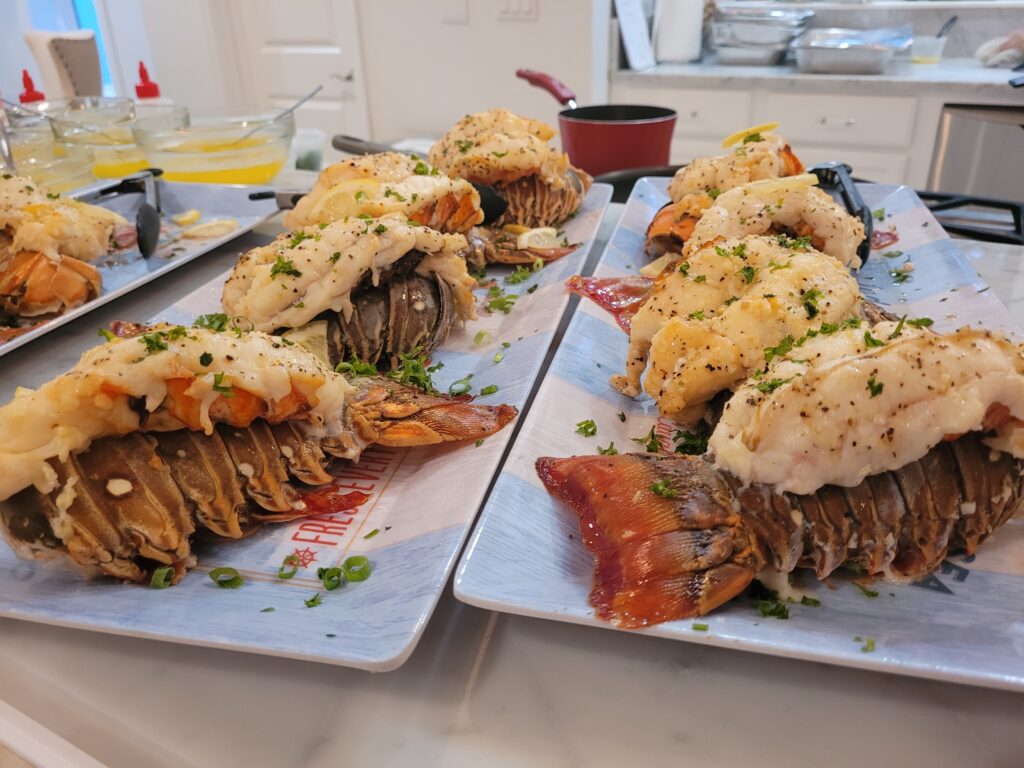 Baked lobster tails on plates with garnish.