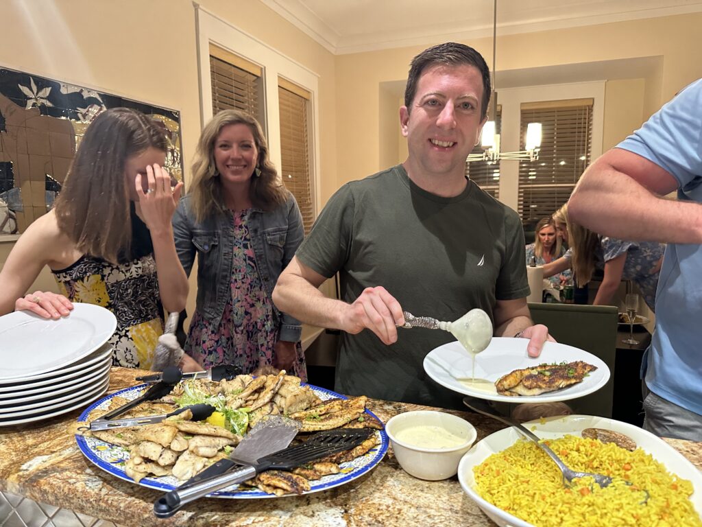 A group of people standing around a table with food.
