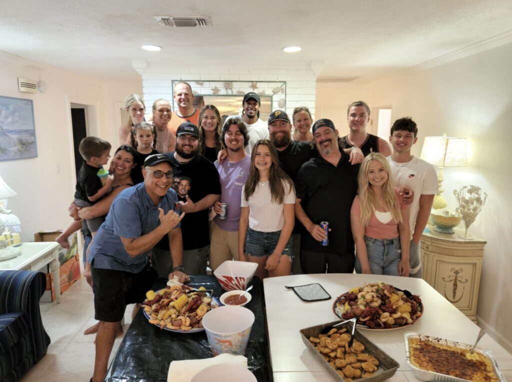 A group of people standing around a table with food.