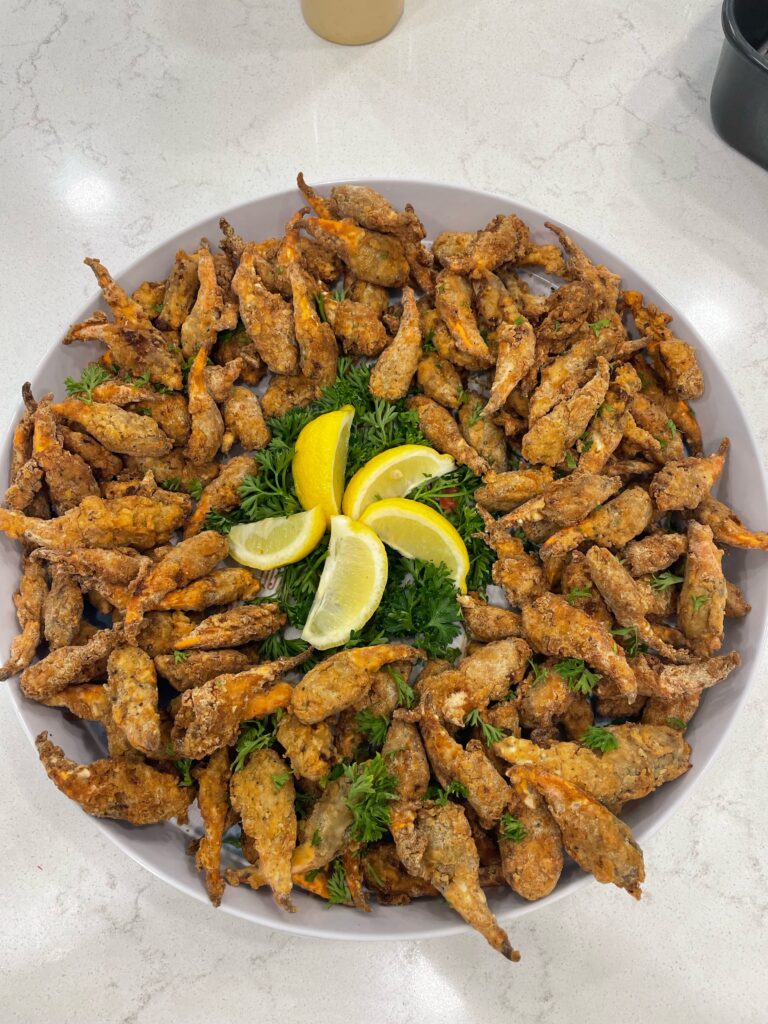 A bowl of food with lemon wedges and greens.